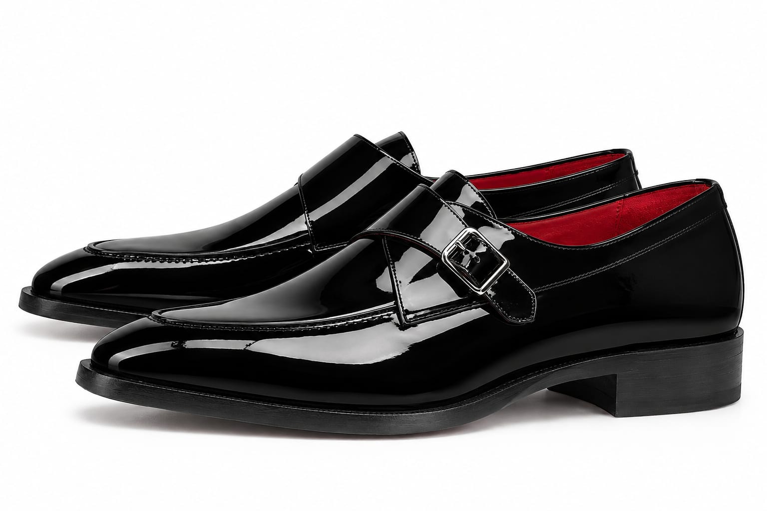 A pair of men's black patent leather double monk loafers with a buckle strap across the instep and a bright red interior lining, shown on a white background.