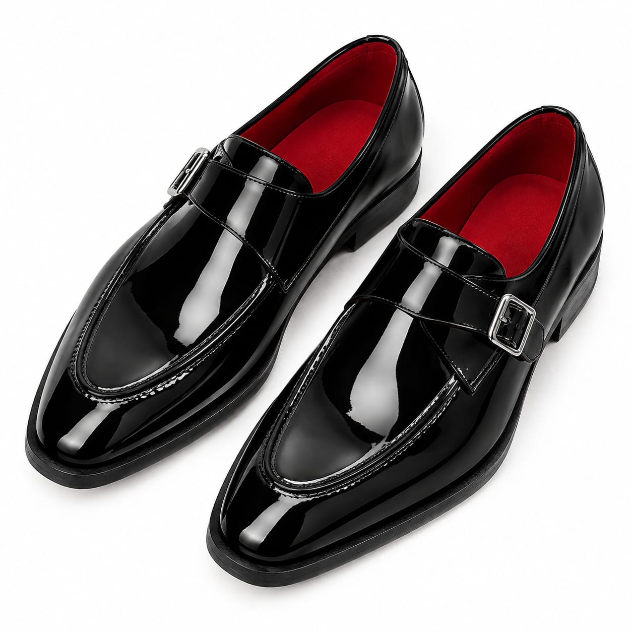 A pair of glossy black patent leather penny loafers with silver buckle straps, shown on a clean white background. The interior lining is a vibrant red.