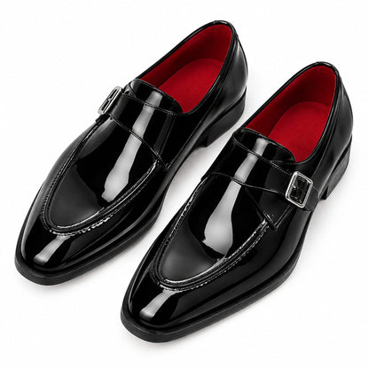 A pair of glossy black patent leather penny loafers with silver buckle straps, shown on a clean white background. The interior lining is a vibrant red.